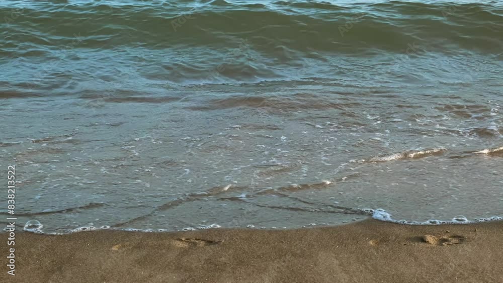 View on legs of people walking by the beach along the water on the sunset. Waves of coastline on volcanic sandy beach. Mediterranean Sea. Vacation concept. Weekend vibe. Slow motion. High quality 4k View on legs of people walking by the beach along the water on the sunset. Waves of coastline on volcanic sandy beach. Mediterranean Sea. Vacation concept. Weekend vibe. Slow motion. High quality 4k