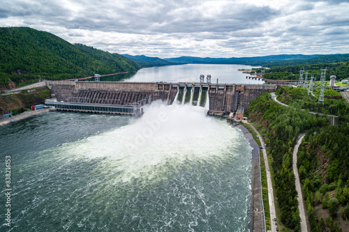 Fotografie Aerial view of concrete dam releasing water into river on cloudy day