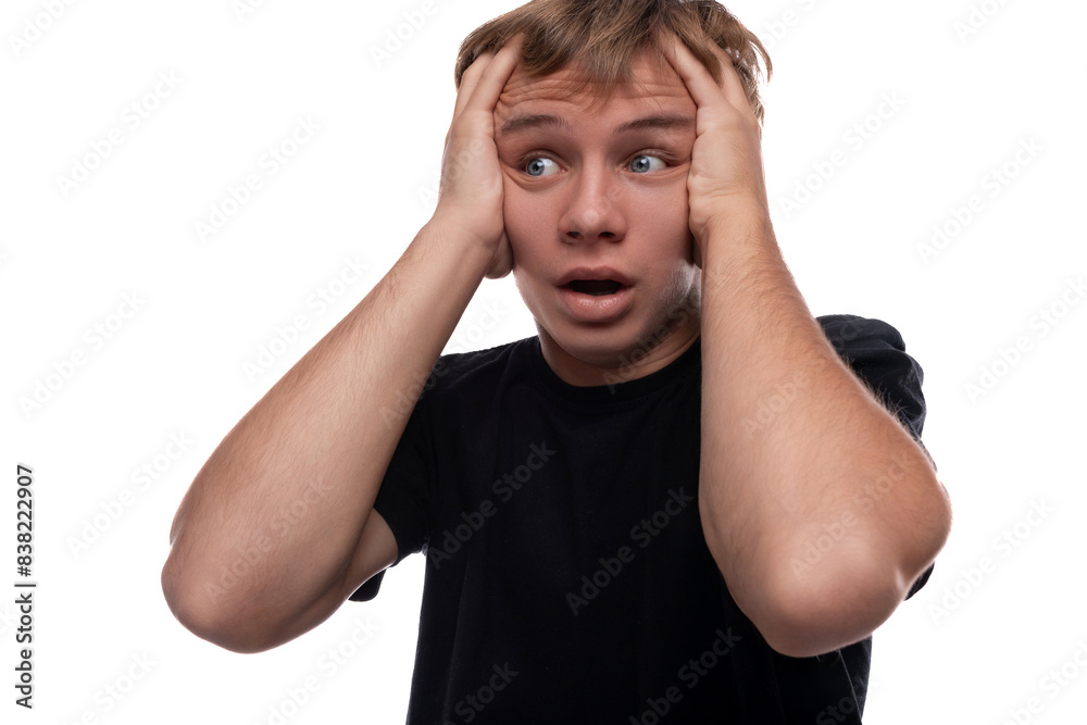 Handsome Caucasian blond teenager guy in a black T-shirt is worried and wants to hide Handsome Caucasian blond teenager guy in a black T-shirt is worried and wants to hide