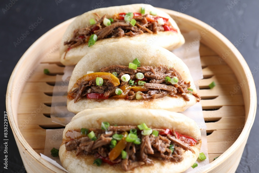 Delicious gua bao in bamboo steamer on black table, closeup Delicious gua bao in bamboo steamer on black table, closeup