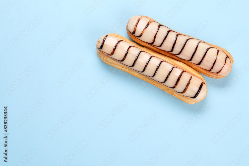 Delicious eclairs covered with glaze on light blue background, top view. Space for text Delicious eclairs covered with glaze on light blue background, top view. Space for text