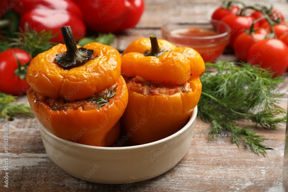 Tasty stuffed peppers in bowl on wooden table, closeup Tasty stuffed peppers in bowl on wooden table, closeup