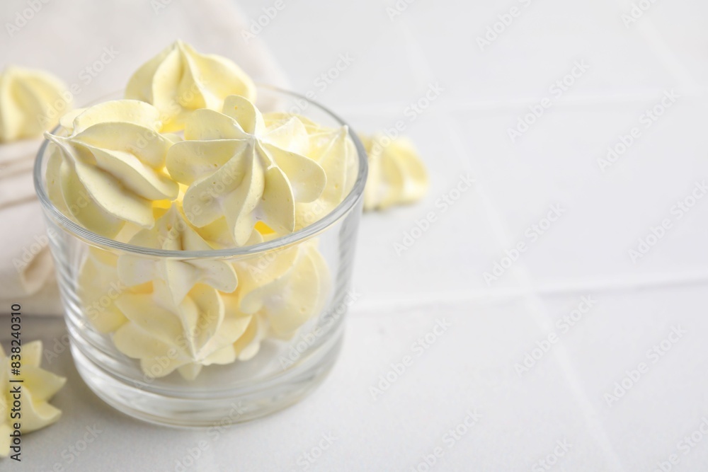 Tasty meringue cookies in glass on white tiled table. Space for text Tasty meringue cookies in glass on white tiled table. Space for text