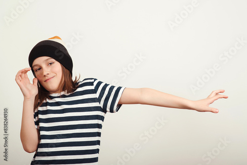 Excited boy having fun and posing at studio. Portrait of eleven years old boy. Boy wearing stylish woolen hat and tshirt.