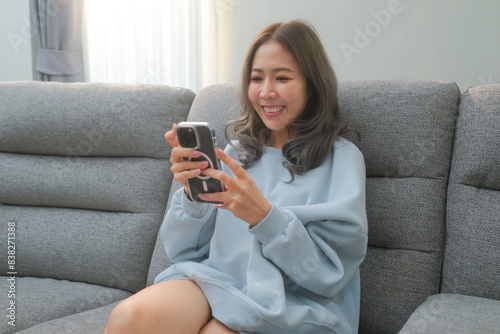 Woman reading messages on mobile phone and video calling with friends On your favorite sofa