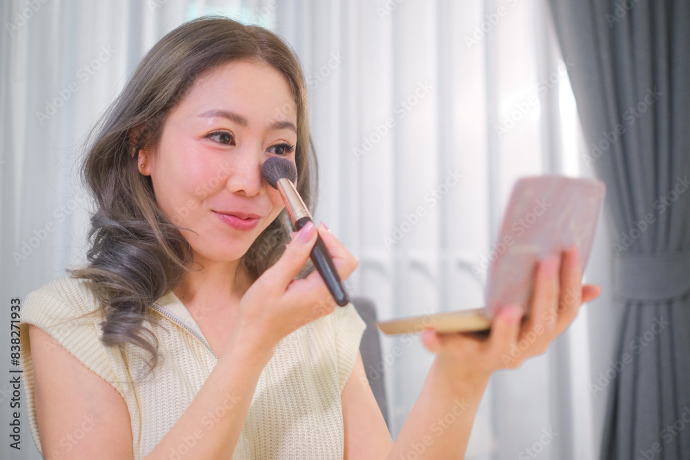 A woman puts on makeup and blush to boost her confidence before leaving the house. A woman puts on makeup and blush to boost her confidence before leaving the house.