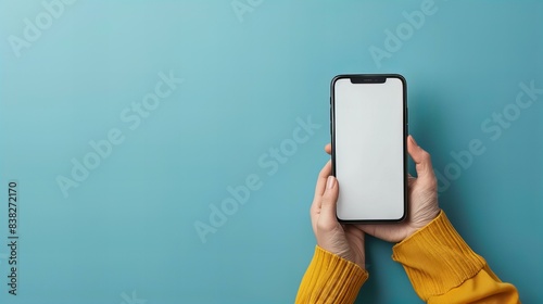 A minimalist image showing hands holding a smartphone with a blank screen against a blue background. This clean and simple composition highlights modern technology and potential customization
