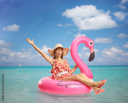 Young happy woman sitting on a flamingo rubber ring