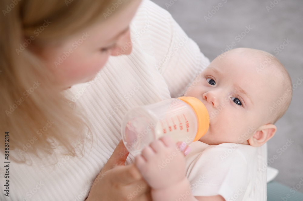 Woman bottle feeds small newborn with formula as alternative to breastfeeding, close-up. Mom takes care of child. Concept of child care, maternity leave, infancy, infant nutrition, professional nanny. Woman bottle feeds small newborn with formula as alternative to breastfeeding, close-up. Mom takes care of child. Concept of child care, maternity leave, infancy, infant nutrition, professional nanny.