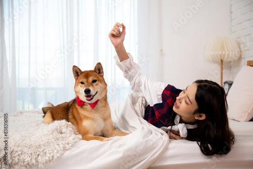 Wallpaper Mural Asian young woman in cozy bedroom playing with her Shiba Inu dog wearing red bow tie on white bed Torontodigital.ca
