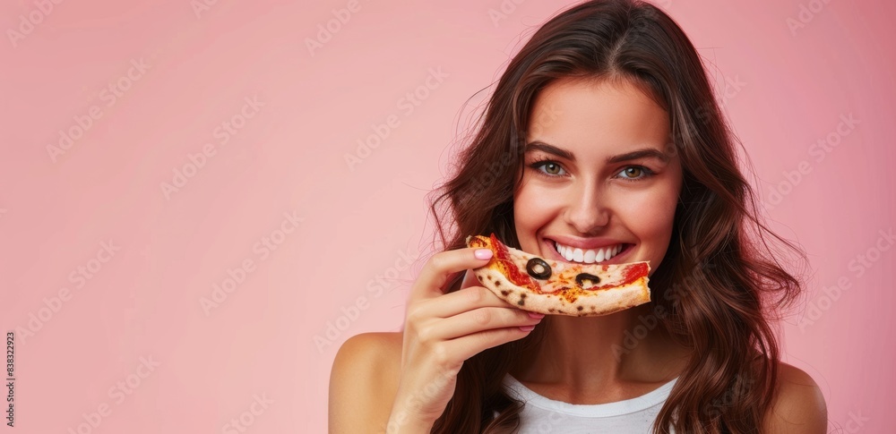 Woman pointing aside at pale pink wall background while biting into tasty pizza slice, Woman pointing aside at pale pink wall background while biting into tasty pizza slice,