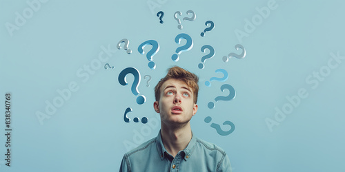 Young man looking up with puzzled expression surrounded by floating question marks, symbolizing confusion and curiosity
