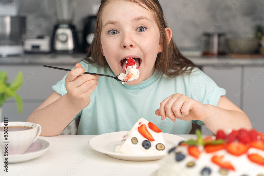 Cheerful little girl eating cake, she puts a large piece of dessert in her mouth. Selected focus. Cheerful little girl eating cake, she puts a large piece of dessert in her mouth. Selected focus.