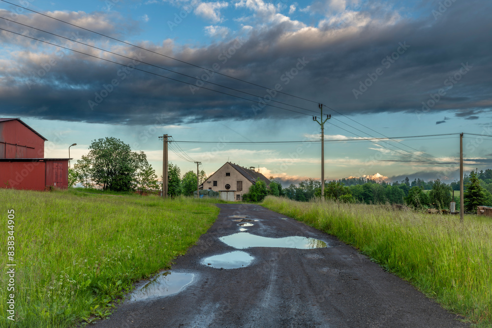 Puddles on village road in color sunset evening in Roprachtice Puddles on village road in color sunset evening in Roprachtice