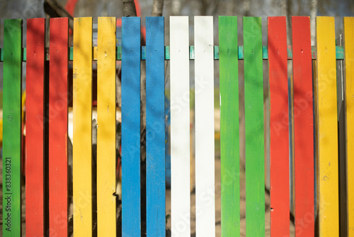 Colored fence made of wood. Boards of different colors. Cheerful hedge. Yard Details.