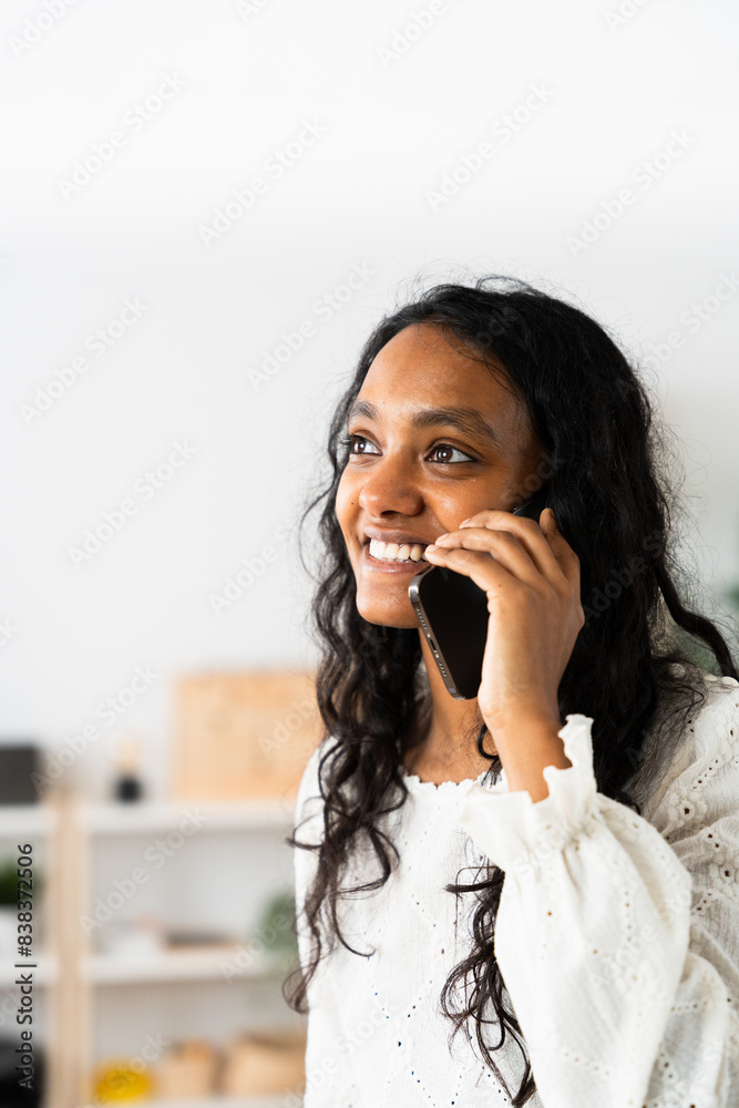 Indian woman talking on phone. Vertical portrait of young entrepreneur thinking with copy space Indian woman talking on phone. Vertical portrait of young entrepreneur thinking with copy space