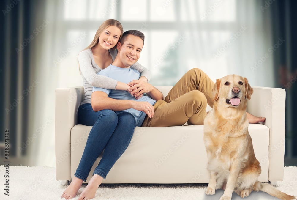 happy couple sitting together on sofa with a dog