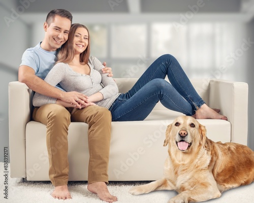 happy couple sitting together on sofa with a dog