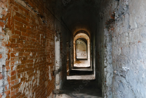 Indoor ruined brick premises with arches, doors and corridors. Old abandoned building. Peeling walls. Horror concept. Destroyed internal rooms. Tunnel.