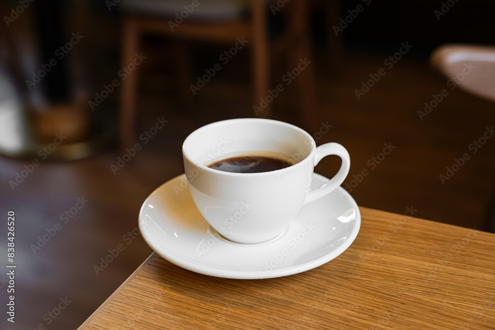 White porcelain cup of black coffee on a saucer in a cafe White porcelain cup of black coffee on a saucer in a cafe