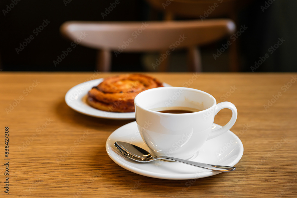 Fototapeta premium Pain aux raisins, bun with raisins and a cup of coffee on wooden table
