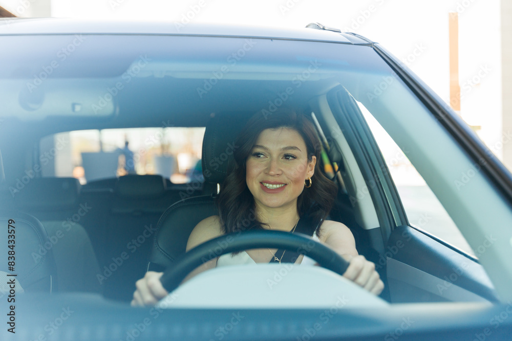 Confident woman smiling as she drives her car, prioritizing safety and comfort in urban environments