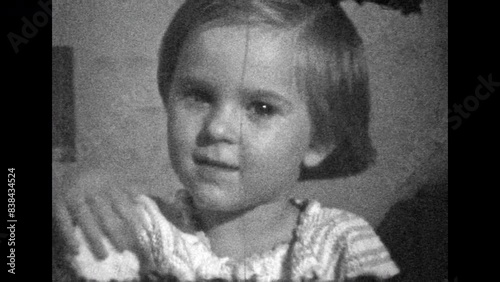 Archive film, little girl serious portrait looking at camera, close up. Creepy, exciting, brilliant child look. Beautiful girl look attentively. Vintage black white movie. Family retro 1980s memories