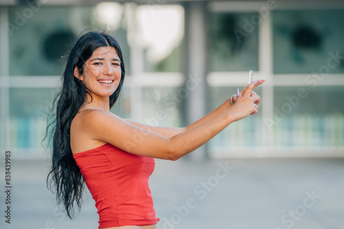 Free Download young latin girl or woman with summer clothes looking at her mobile phone or smartphone - GFXLoad