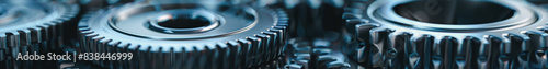 A close up of a set of gears with a metallic look. The gears are all different sizes and are arranged in a row. Concept of precision and complexity, as gears are often used in machinery
