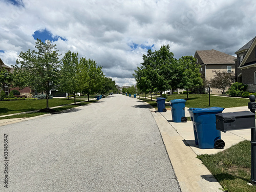 Blue trash cans line the street on trash day in an Indiana Neighborhood with copy space.