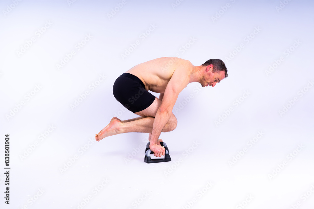 Obraz premium Shirtless muscular athlete doing push-up on push up bars. Full body man on white studio background.