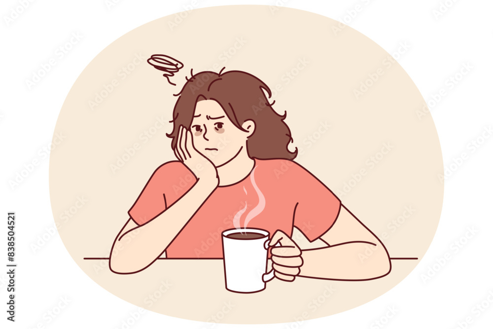 Tired woman with sad face drinks hot coffee and does not want to go to work due to lack of sleep. Upset girl is sitting at table with mug of coffee on Monday morning and is sad because weekend is over Tired woman with sad face drinks hot coffee and does not want to go to work due to lack of sleep. Upset girl is sitting at table with mug of coffee on Monday morning and is sad because weekend is over