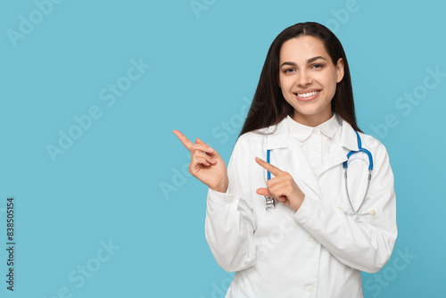 Portrait of female doctor pointing at something on blue background