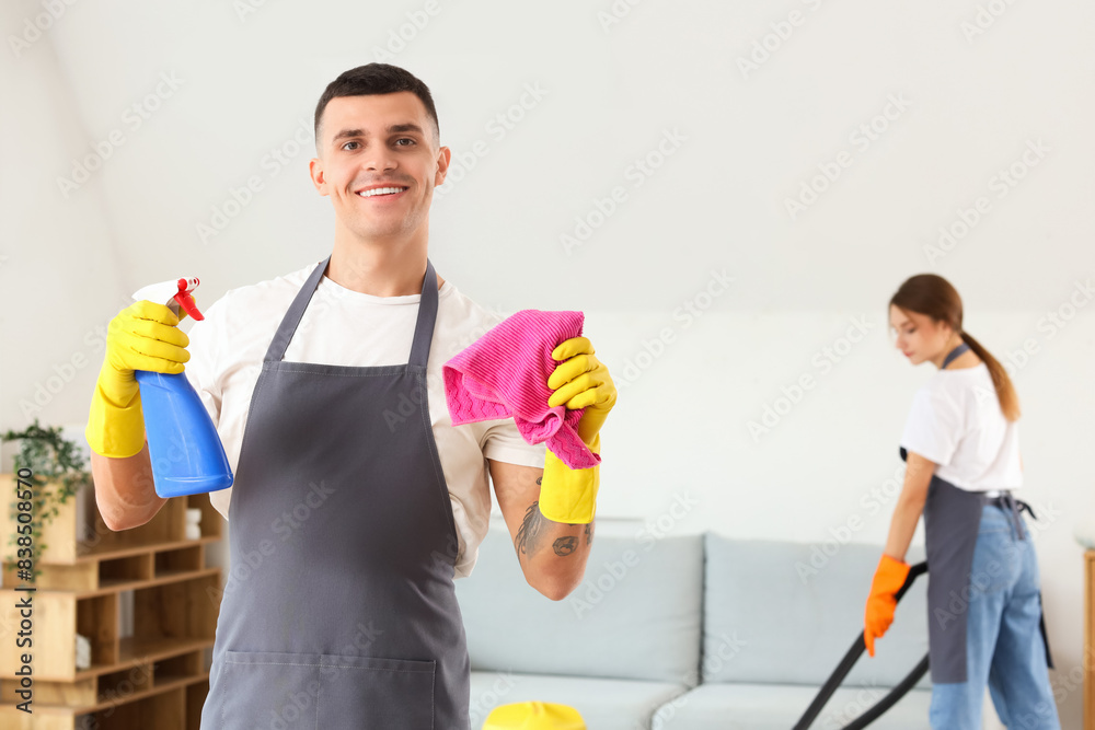 Male janitor with rag and detergent in room Male janitor with rag and detergent in room