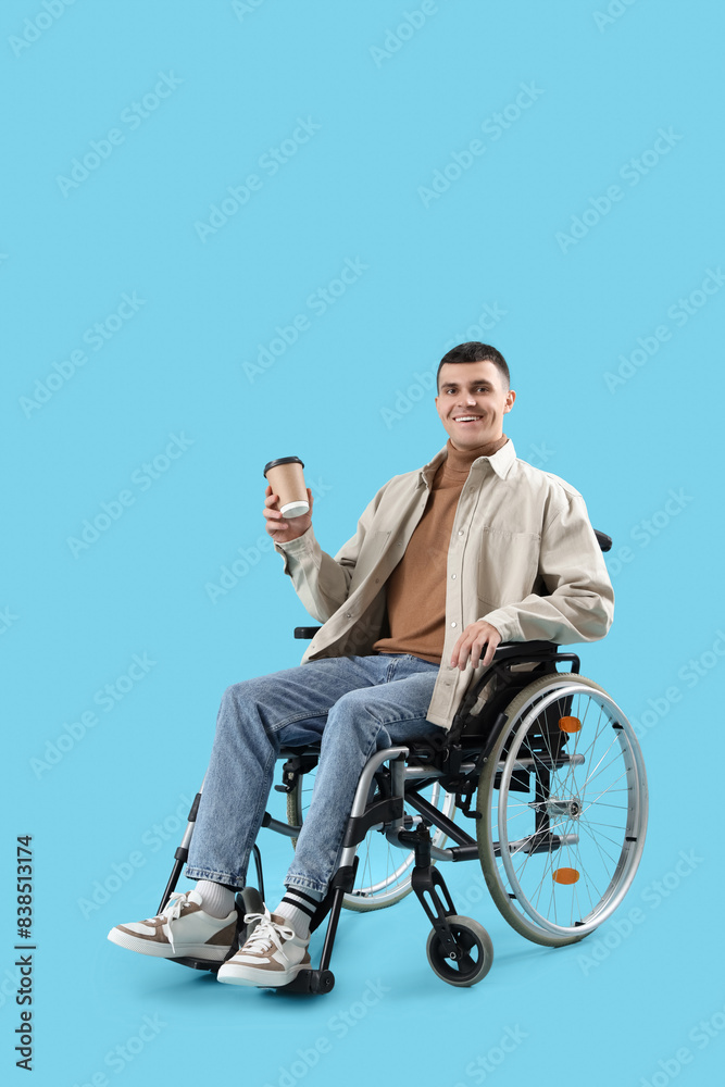 Happy young man in wheelchair with coffee cup on blue background Happy young man in wheelchair with coffee cup on blue background