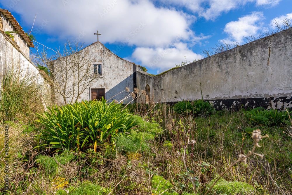 Old countryside church surrounded by overgrown plants and stone walls Old countryside church surrounded by overgrown plants and stone walls