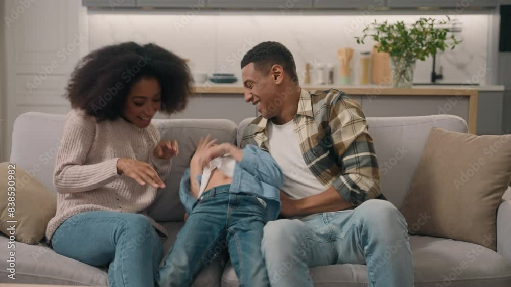 Playful parents mother mom female woman father dad male man tickling hug sincere laughing funny game ticklish having fun little boy child son kid living room bed. African American family cuddle indoor Playful parents mother mom female woman father dad male man tickling hug sincere laughing funny game ticklish having fun little boy child son kid living room bed. African American family cuddle indoor