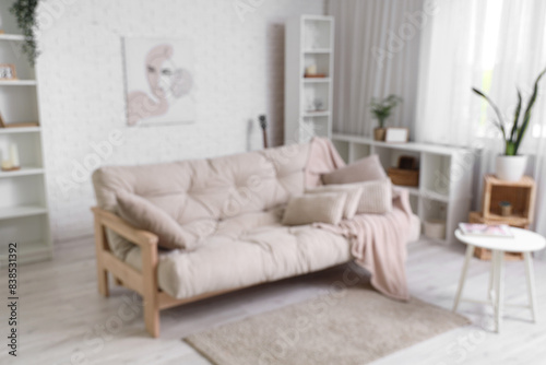 Beautiful interior of living room with cozy sofa, shelving units and coffee table, blurred view © Pixel-Shot