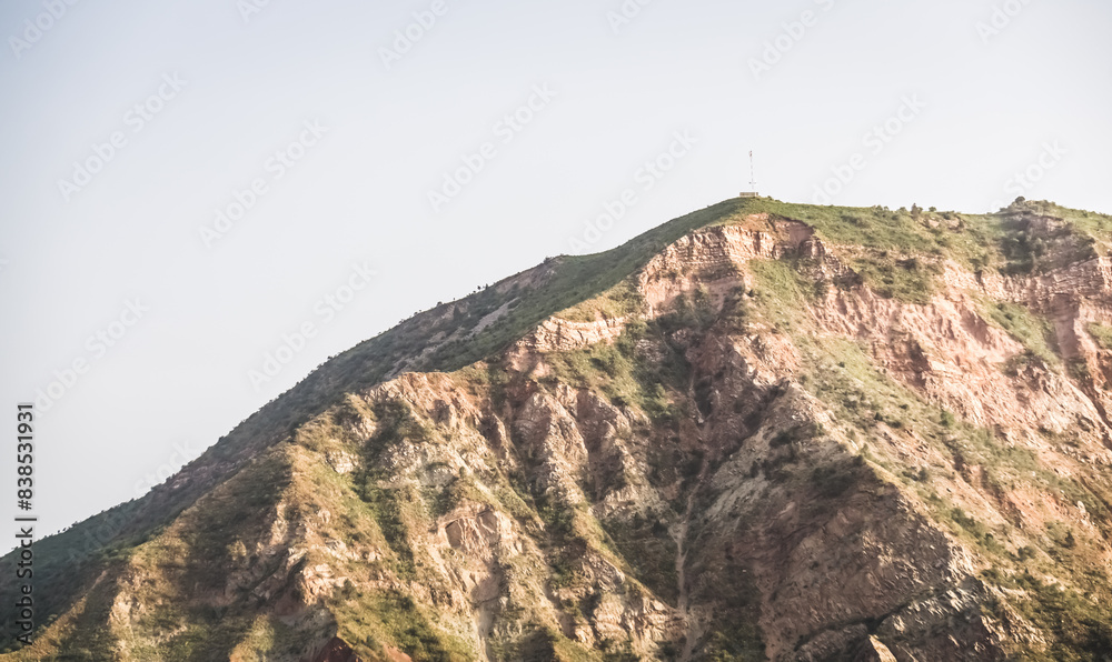 Texture of a rocky mountain range with rocky cliffs and vegetation in the evening at sunset in the mountains of Tajikistan Texture of a rocky mountain range with rocky cliffs and vegetation in the evening at sunset in the mountains of Tajikistan