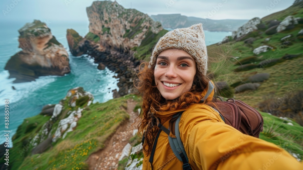 Naklejka premium Travel Selfie. Backpacker Woman Capturing Adventure on Stunning Cantabria Cliff