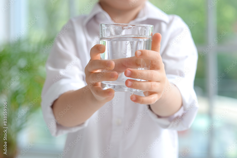 Cute little girl with glass of water near window at home, closeup Cute little girl with glass of water near window at home, closeup