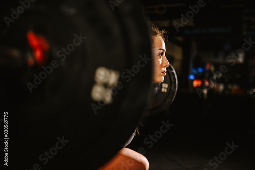 Portrait of a muscular woman training in a fitness gym while lifting barbell