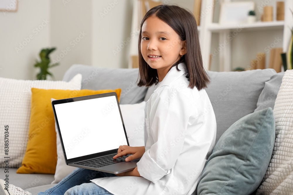 Little Asian girl using laptop on sofa at home Little Asian girl using laptop on sofa at home