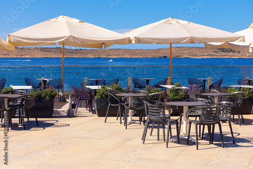 Outdoor restaurant with a sea view. Summer terrace with tables and chairs under white umbrellas © russieseo