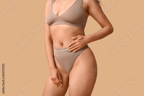 Beautiful young African-American woman in stylish underwear on beige background, closeup