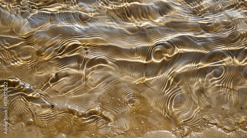 The rippled patterns on the wet sand formed by the ebb and flow of the waves give the surface a smooth and wavy texture photo