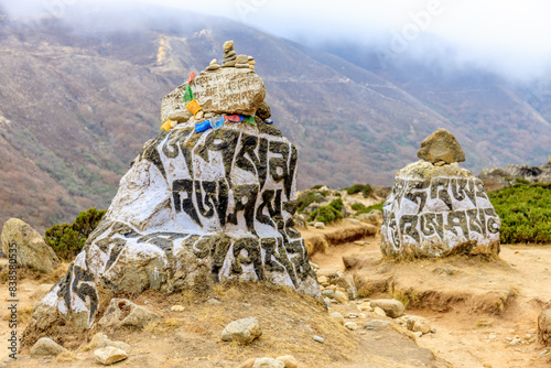 Nepal sacred stones mani with mantra written and carved on the surface. Prayer stones shire on the mountain trekking path on Everest Base Camp trek. Nepali buddhist mantra Om Mani Padme Hum on rock photo