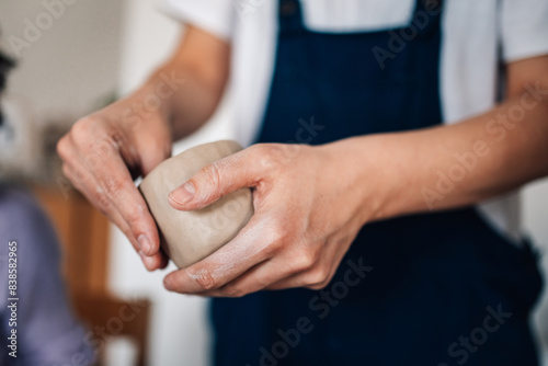 Close up of female artisan's hands modeling clay mug at ceramics studio