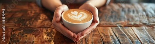 a barista female hands (hands cupped), holding a cup of cappuccino with heart