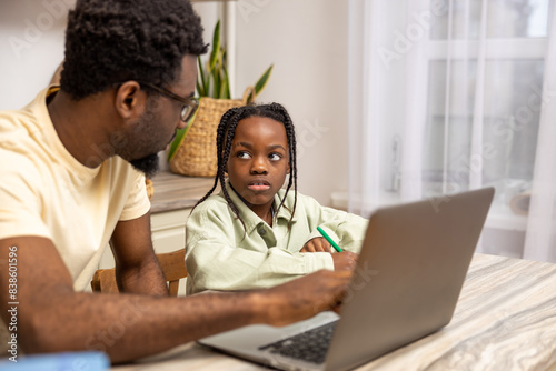African American father helps his daughter with lessons during distance education
